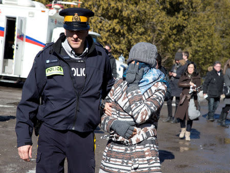 A woman from a family of four is taken into custody by Royal Canadian Mounted Police (RCMP) officers after crossing the U.S.-Canada border into Hemmingford, Quebec, Canada February 20, 2017. REUTERS/Christinne Muschi