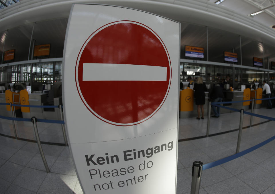 Passengers stand behind an exit sign near Lufthansa counters as flight attendants of German Lufthansa airline went on an 24-hour-strike for higher wages at the airport in Munich, southern Germany, on Friday, Sept. 7, 2012. (AP Photo/Matthias Schrader)