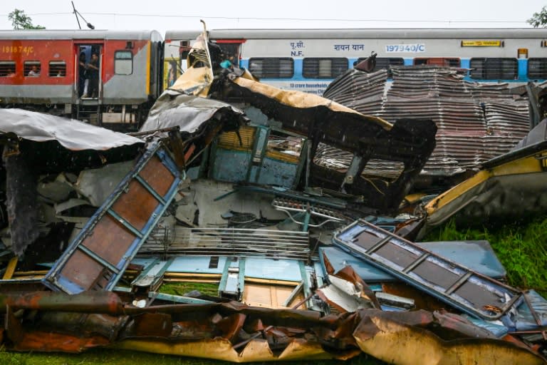 A train drives past the wreckage of another train crash in India's West Bengal state on June 18 (DIBYANGSHU SARKAR)