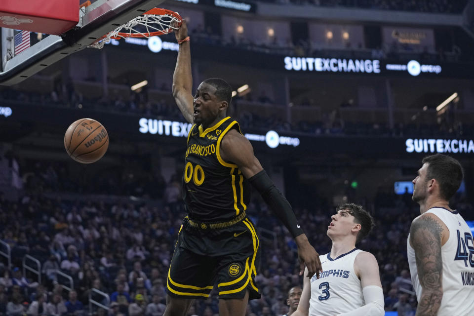 Golden State Warriors forward Jonathan Kuminga (00) dunks next to Memphis Grizzlies forward Jake LaRavia (3) during the first half of an NBA basketball game Wednesday, March 20, 2024, in San Francisco. (AP Photo/Godofredo A. Vásquez)