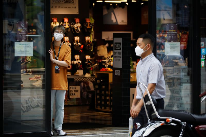 A shop assistant waits for a customer at Myeongdong shopping district which is nearly empty amid the coronavirus disease (COVID-19) pandemic in Seoul