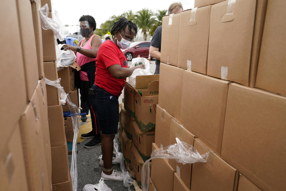 Sharon Smith-Butler, right, loads produce into a bag as she works with other volunteers at a food distribution for local residents sponsored by Feeding South Florida, Thursday, Jan. 28, 2021, in Florida City, Fla. (AP Photo/Lynne Sladky)