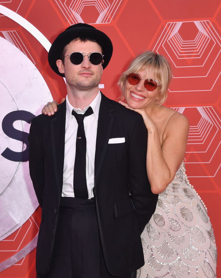 Con un diseño de seda con bordados plateados e inspiración setentera y gafas de cristal rosado, la actriz Sienna Miller acudió a los premios para acompañar a su pareja, el actor inglés Tom Sturridge  