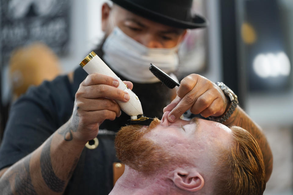 Braunson McDonald has his beard trimmed by Luis Lopez, owner of Orange County Barbers Parlor, on Wednesday, July 15, 2020, in Huntington Beach, Calif. Gov. Gavin Newsom this week ordered that indoor businesses like salons, barber shops, restaurants, movie theaters, museums and others close due to the spread of COVID-19. (AP Photo/Ashley Landis)