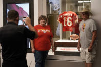 Fans have their photos made while standing next to the jersey of former Kansas City Chiefs quarterback Len Dawson before the start of an NFL preseason football game Thursday, Aug. 25, 2022, in Kansas City, Mo. Dawson, who helped the Kansas City Chiefs to their first Super Bowl title and is in the Pro Football Hall of Fame as a player and broadcaster, died Wednesday at the age of 87. (AP Photo/Charlie Riedel)