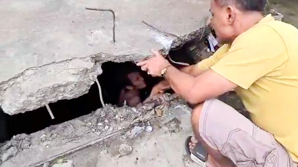 A officer tries to pull the man from the sewer. Source: ViralPress/Australscope