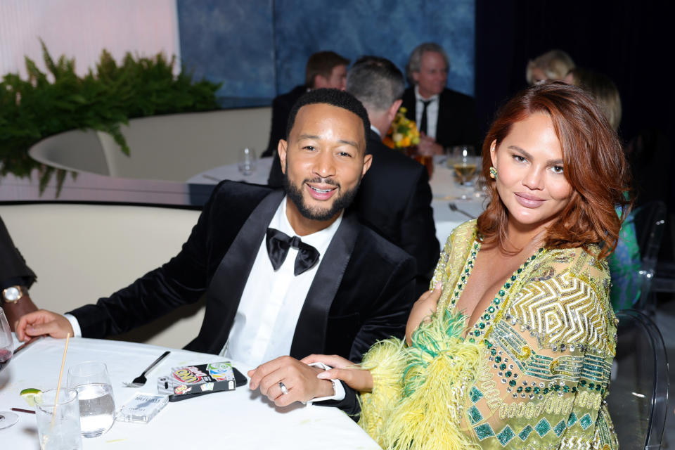 John Legend and Chrissy Teigen smiling for a photo at red carpet