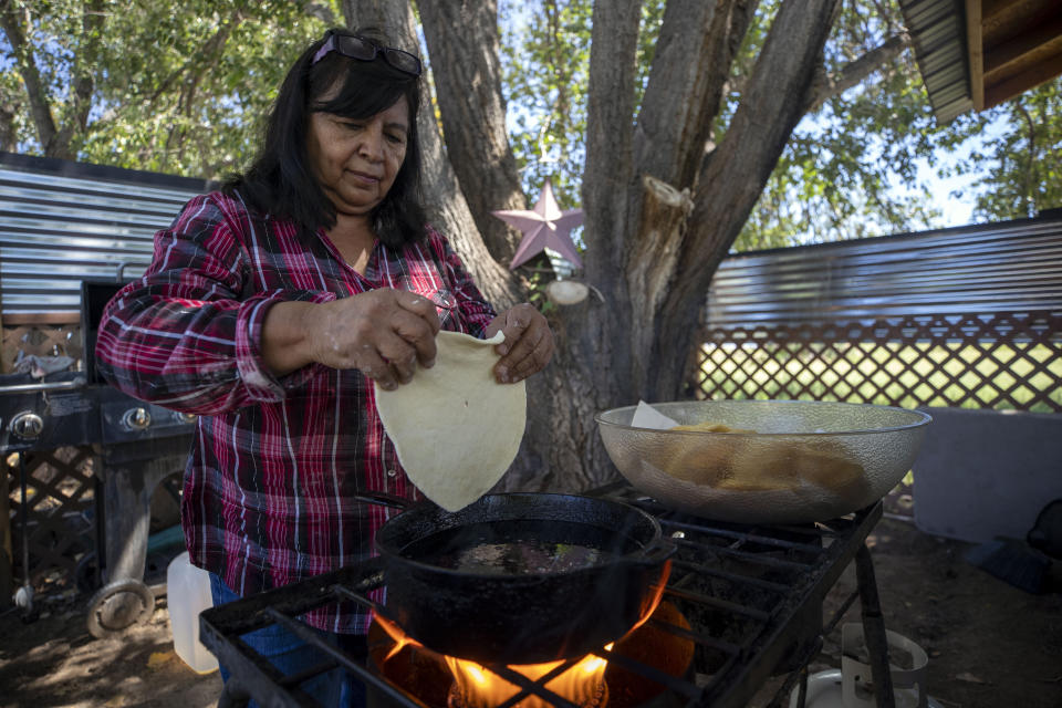 Norma Naranjo fries sopapillas to feed her friends and relatives at her home in Ohkay Owingeh, formerly named San Juan Pueblo, in northern New Mexico, Sunday, Aug. 21, 2022. Naranjo says their grandfathers used to tell them not to plant until the snow disappeared from the peaks. As the climate changes, she says snowfall is increasingly rare. (AP Photo/Andres Leighton)