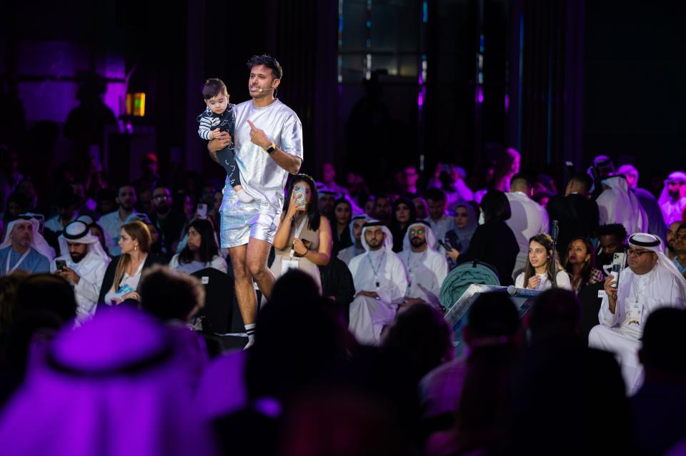 A man onstage presenting a speech holding a young child