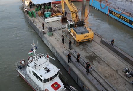 Rescue personnel arrive as a floating crane salvages the wreckage of a capsized tourist boat after an accident which killed several people in the Danube river near Margaret bridge, in Budapest