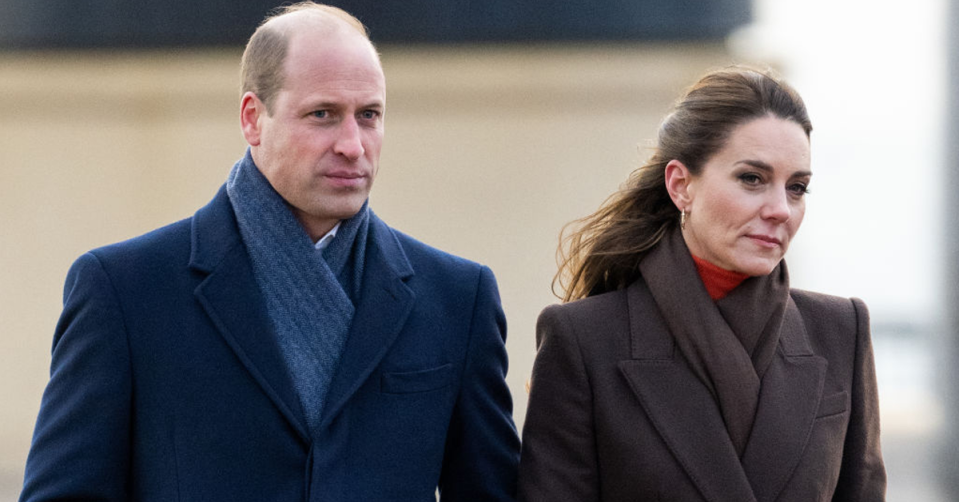 Prince William and Kate Middleton walk outside with coats on.