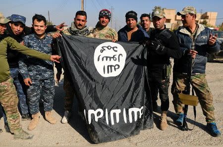 Iraqi security forces members pose with a seized Islamic State flag after driving out its miitants from Mosul's airport south west Mosul, Iraq, February 23, 2017. REUTERS/Zohra Bensemra