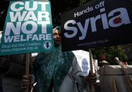 An activist holds placards during an event organised by Stop the War Coalition to protest against potential UK involvement in the Syrian conflict in Whitehall, London.