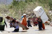 Colombianos cargan sus pertenencias a través del río Táchira. REUTERS/Jose Miguel Gomez