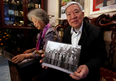 Former Deputy Defense Minister and former Vietnam War pilot Lieutenant General Tran Hanh sits next to his wife Captain Le Thi Xuyen and shows a May 1994 archive photo of late North Korean Kim Il Sung (C, front), late Vietnamese Defence Minister General Doan Khue (4th L, front) and himself (R, front) standing with Vietnamese military delegation, at his home in Hanoi, Vietnam February 14, 2019. Picture taken February 14, 2019. REUTERS/Kham