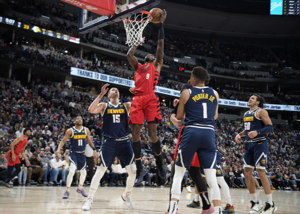 Portland Trail Blazers forward Jerami Grant, center, drives the lane between Denver Nuggets center Nikola Jokic, left, and forward Michael Porter Jr. in the first half of an NBA basketball game Tuesday, Jan. 17, 2023, in Denver. (AP Photo/David Zalubowski)