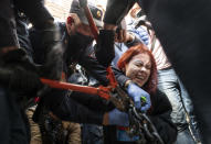 Police try to cut the handcuffs off a woman who handcuffed herself to a fence during a rally supporting Khabarovsk region's governor Sergei Furgal in St.Petersburg, Russia, Saturday, Aug. 1, 2020. Thousands of demonstrators rallied Saturday in the Russian Far East city of Khabarovsk to protest the arrest of the regional governor, continuing a three-week wave of opposition that has challenged the Kremlin. (AP Photo/Dmitri Lovetsky)