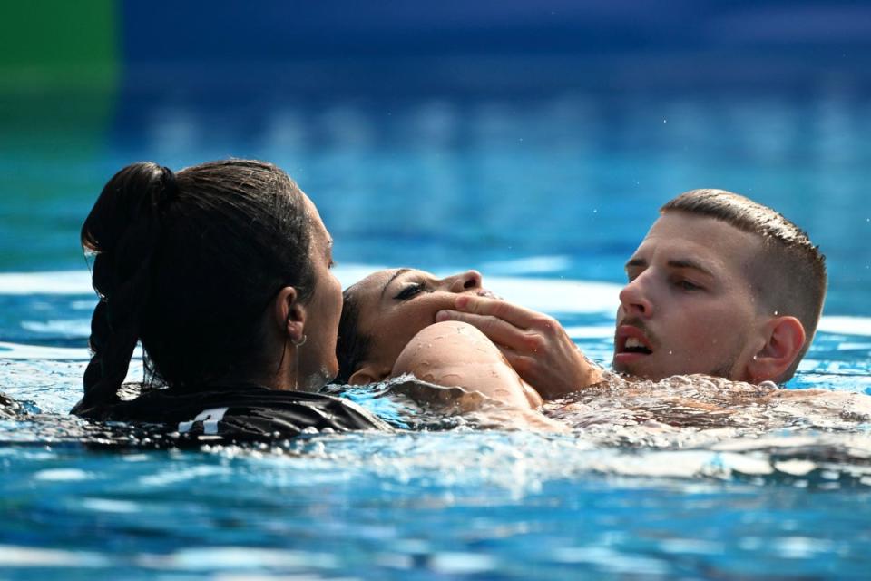 The swimmer is carried to the edge of the water (AP)