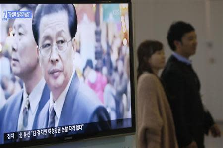 A couple walks past a television showing a report on Jang Song Thaek, North Korean leaders' uncle, at a railway station in Seoul December 3, 2013. REUTERS/Kim Hong-Ji