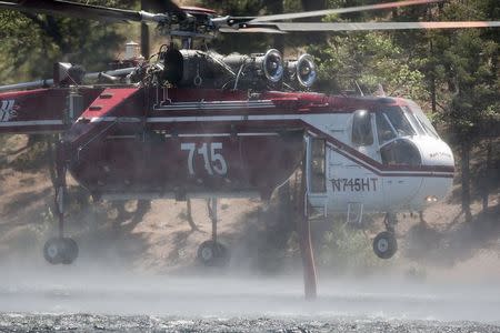 A firefighting helicopter fills up with water from Jenks Lake as firefighters battle the Lake Fire in the San Bernardino National Forest, California June 19, 2015. REUTERS/David McNew