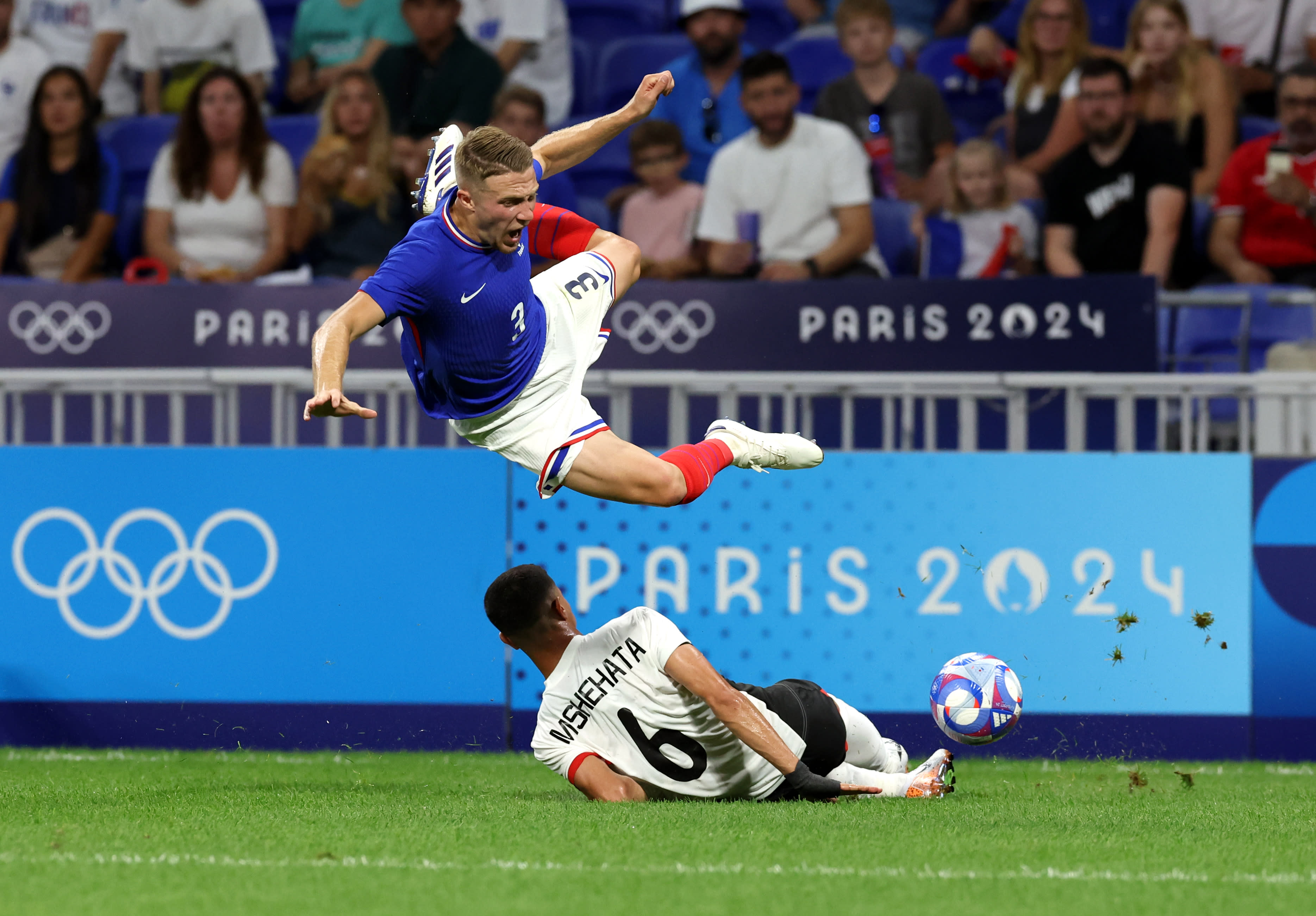 LYON, FRANCE - AUGUST 05: Adrien Truffert #3 of Team France jumps over Shehata Mohamed #6 of Team Egypt during the Men's semifinal match between France and Egypt during the Olympic Games Paris 2024 at Stade de Lyon on August 05, 2024 in Lyon, France. (Photo by Claudio Villa/Getty Images)