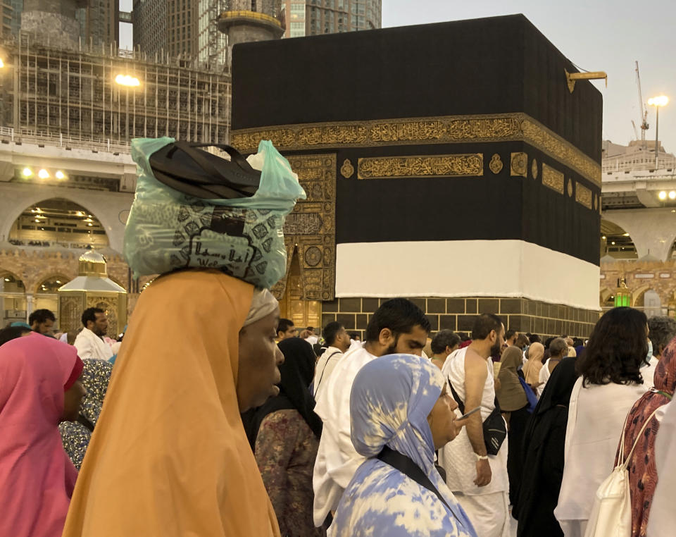 An African Muslim pilgrim carries her luggages as she circumambulates around the Kaaba, the cubic building at the Grand Mosque, in the Saudi Arabia's holy city of Mecca, Tuesday, July 5, 2022. Saudi Arabia is expected to receive one million Muslims to attend Hajj pilgrimage, which will begin on July 7, after two years of limiting the numbers because coronavirus pandemic. (AP Photo/Amr Nabil)