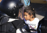 A migrant girl looks at Mexican National Guardsmen at the border crossing between Guatemala and Mexico in Tecun Uman, Guatemala, Saturday, Jan. 18, 2020. More than a thousand Central American migrants surged onto the bridge spanning the Suchiate River, that marks the border between both countries, as Mexican security forces attempted to impede their journey north. (AP Photo/Marco Ugarte)