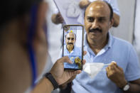 An Indian health worker takes photograph of a man while registering names before administering COVISHIELD vaccine at the Guwahati Medical College hospital in Gauhati, India, Monday, March 1, 2021. India is expanding its COVID-19 vaccination drive beyond health care and front-line workers, offering the shots to older people and those with medical conditions that put them at risk. (AP Photo/Anupam Nath)