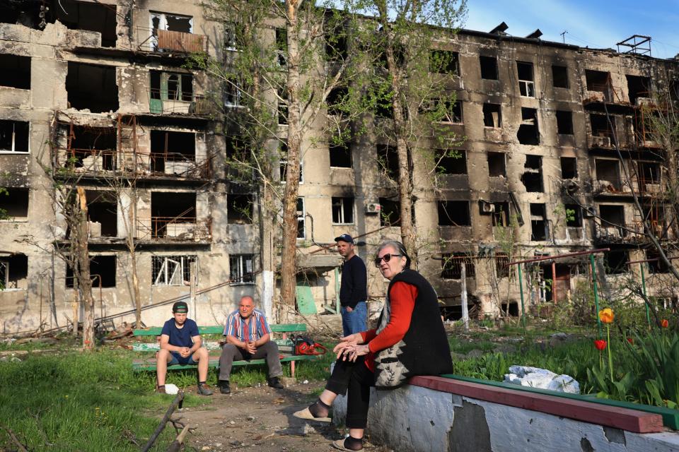 Residents sit in the yard of their damaged building in Mariupol, Ukraine, on April 29, 2022.