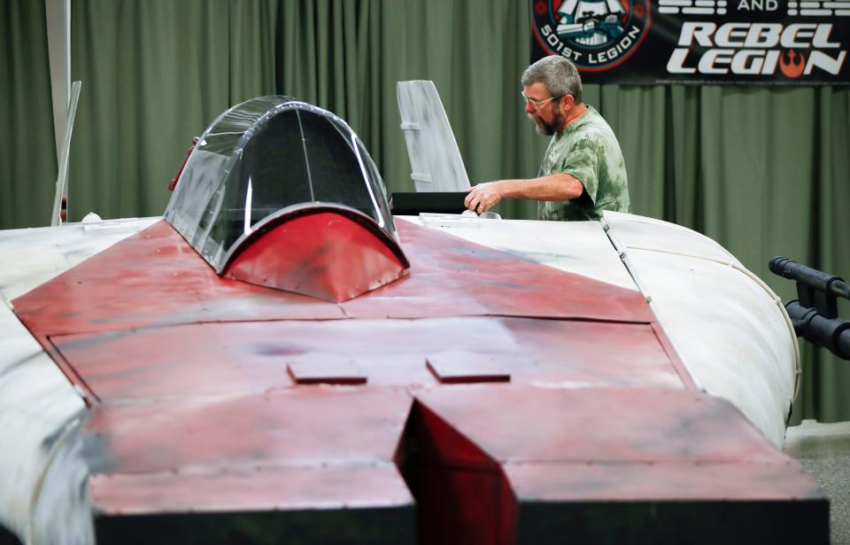 Patrick Gilmore, with the 501st and Rebel Legion Star Wars fan organization, sets up an A-wing starfighter at VisionCon on Thursday, Oct. 12, 2023.