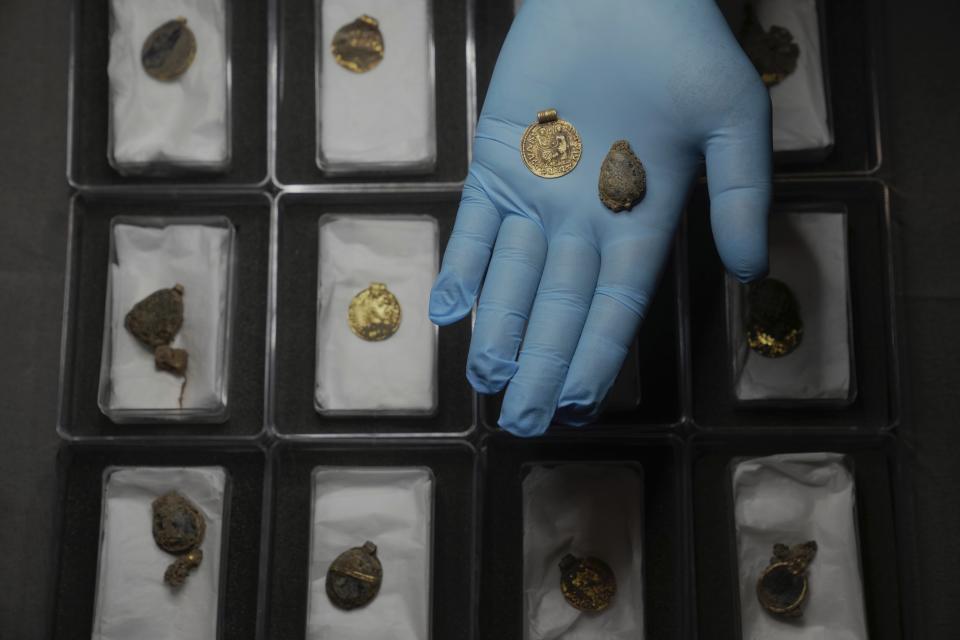 Liz Barham, senior conservator of the Museum of London Archaeology, displays an early medieval gold and gemstone necklace during a photo call, in London, Tuesday, Dec. 6, 2022. Archaeologists say a 1,300-year-old gold and gemstone necklace found during construction of a housing development marks the grave of a powerful woman who may have been an Anglo-Saxon aristocrat or early Christian religious leader in Britain. (AP Photo/Kin Cheung)