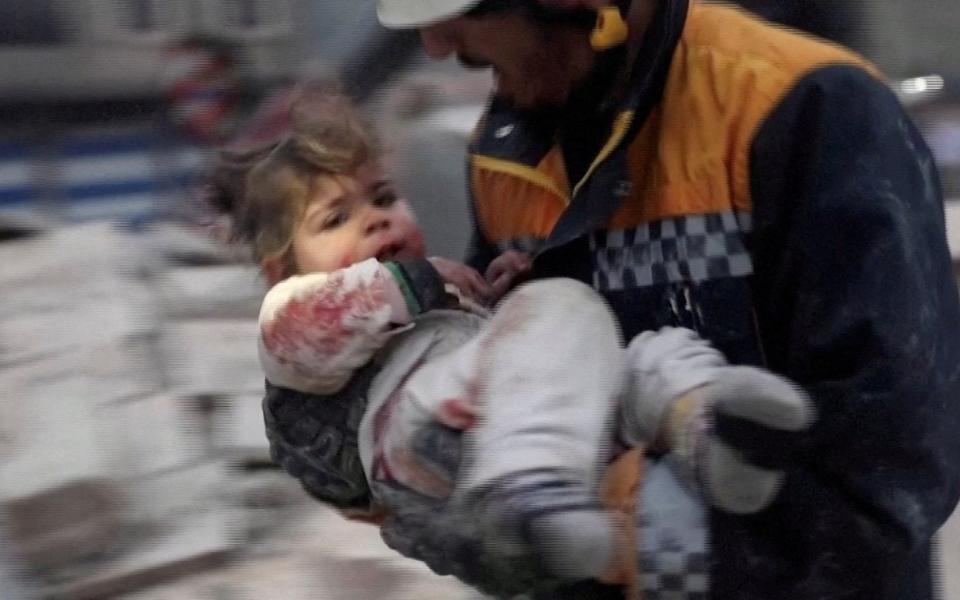 A rescuer carries a Syrian toddler, Raghad Ismail, away from the rubble of a building following an earthquake in rebel-held Azaz, Syria - Reuters