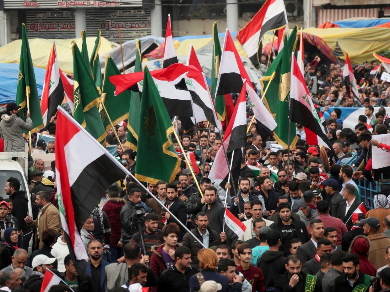 Protesters hold Popular Mobilisation Forces (PMF) and Iraqi flags as they march towards Tahrir Square in Baghdad, Iraq, 6 December, 2019: Hadi Mizban/AP