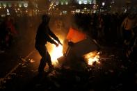 A man throws a dumpster on a fire during a protest in Madrid November 4, 2013. Spain's labor unions called for an indefinite strike from Tuesday in Spain's capital for the street cleaning and park maintenance sectors in protest against announced layoffs that could affect around a thousand municipal workers, according to local media. (REUTERS/Juan Medina)