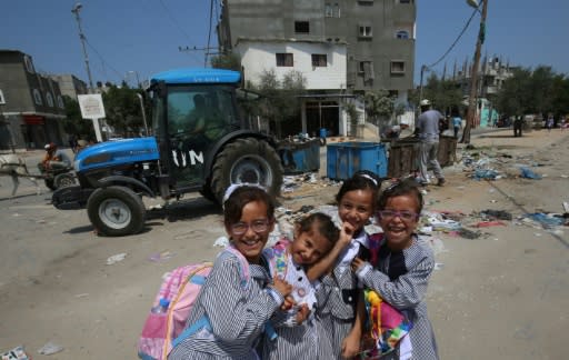 Palestinian schoolgirls pose near a UN Relief and Works Agency (UNRWA) tractor in Rafah refugee camp in the Gaza Strip, on September 1, 2018 following Washington's announcement it was ending all funding