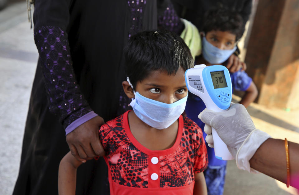 FILE - A health worker checks the temperature of a child, who had been stranded for weeks due to the lockdown to curb the spread of new coronavirus, before allowing her to board a bus in Bangalore, India, Wednesday, May 6, 2020, as the country partially relaxed its lockdown. (AP Photo/Aijaz Rahi, File)