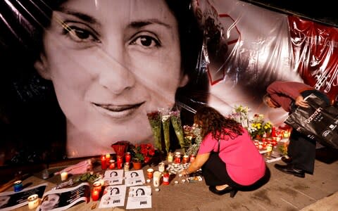 People lay flowers and candles at a makeshift memorial during a vigil for the journalist  - Credit: REUTERS/Darrin Zammit Lupi