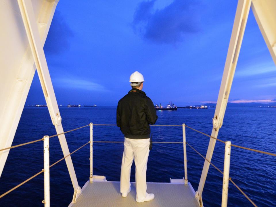 A cruise ship employee standing on a deck on Cunard's Queen Victoria cruise ship and looking out to sea.