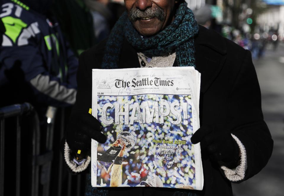 A fan stands with a signed newspaper along 4th Avenue in downtown at the Super Bowl victory parade for the Seattle Seahawks in Seattle, Washington February 5, 2014. Up to 500,000 Seattle Seahawks fans were expected to brave sub-freezing temperatures to celebrate the football team's first Super Bowl title at a parade set to wind through the city's downtown on Wednesday. REUTERS/Jason Redmond (UNITED STATES - Tags: SPORT FOOTBALL)