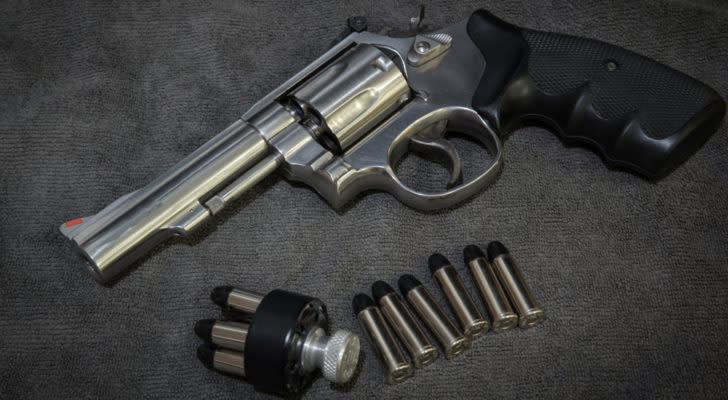 Image of a pistol and several bullets laying on a dark grey surface