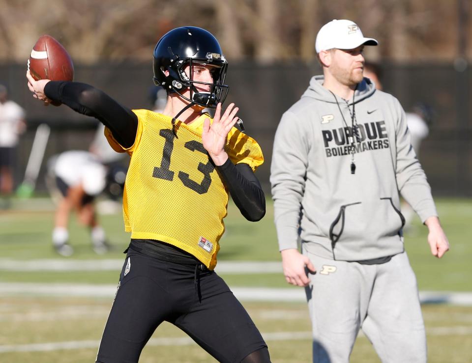 Freshman quarterback Jack Plummer with a pass under the watchful eye of quarterbacks coach and co-offesnive coordinator Brian Brohm during the first day of Purdue spring football practice Monday, February 26, at the Bimel Practice Complex.