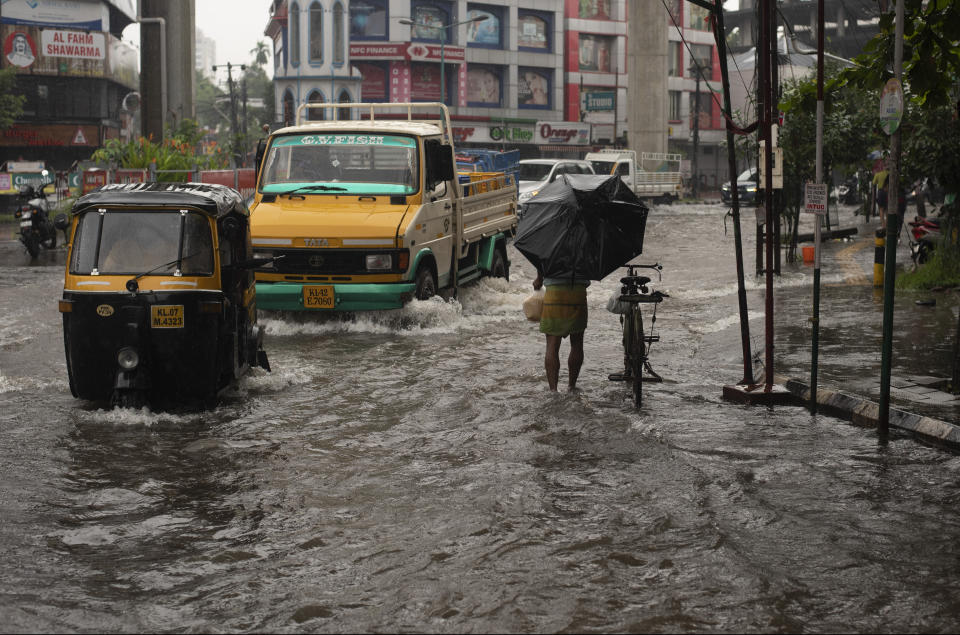 Vehicles move through a waterlogged street during heavy rainfall in Kochi, Kerala state, India, Friday, Aug. 7, 2020. A mudslide triggered by heavy monsoon rain and flooding killed at least five people in the state on Friday, police said. (AP Photo/R S Iyer)