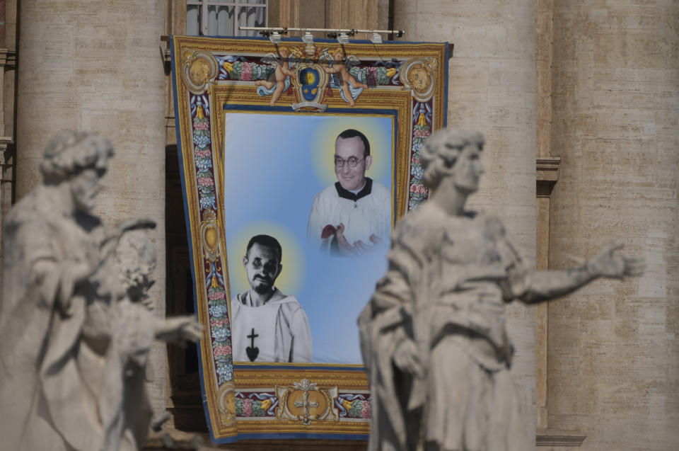 The tapestry depicting Giustino Maria Russolillo (1891-1955), top, and Charles de Foucauld (1858-1916), hangs in St. Peter's Square at The Vatican, Sunday, May 15, 2022, during their canonization mass celebrated by Pope Francis. Francis created ten new saints on Sunday, rallying from knee pain that has forced him to use a wheelchair to preside over the first canonization ceremony at the Vatican in over two years. (AP Photo/Gregorio Borgia)