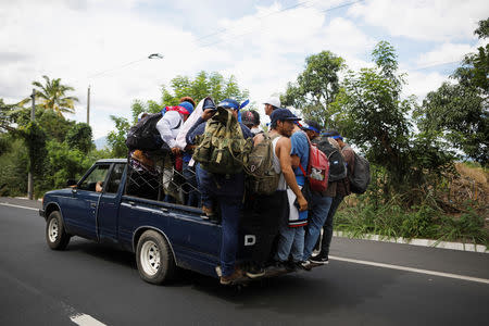 People ride in the back of a pick-up truck in a caravan of migrants from El Salvador en route to the United States, in Ateos, El Salvador, October 28, 2018. REUTERS/ Jose Cabezas