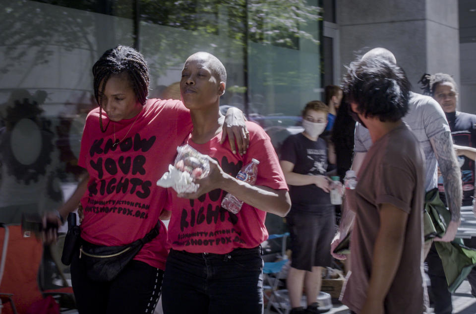 Demetria Hester, second from left,leaves the Multnomah County Justice Center on Monday, Aug. 10, 2020, in Portland, Ore. Hester became a leading activist in the racial justice movement after she was assaulted by a white supremacist three years ago. Authorities said Hester won't be charged following her arrest early Monday. Hester had been booked on suspicion of disorderly conduct and interfering with a police officer during the protest that began Sunday night. Hester’s arrest drew a sharp rebuke from national Black Lives Matter activists, who are increasingly focusing on demonstrations in Oregon’s largest city. (Brooke Herbert/The Oregonian via AP)