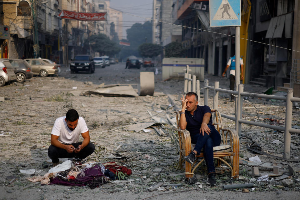 Palestinians sit on a street in Gaza City near the Watan Tower, which was destroyed in Israeli airstrikes on Sunday. (Mohammed Salem/Reuters)