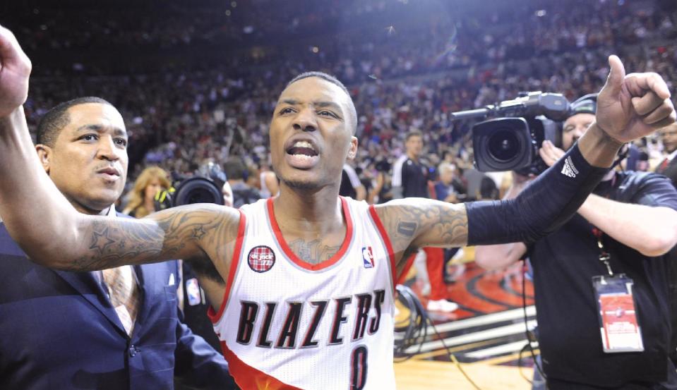 Portland Trail Blazers' Damian Lillard, center, celebrates with fans, his winning shot against the Houston Rockets during the last .9 of a second of game six of an NBA basketball first-round playoff series game in Portland, Ore., Friday May 2, 2014. The Trail Blazers won the series in a 99-98 win. (AP Photo/Greg Wahl-Stephens)