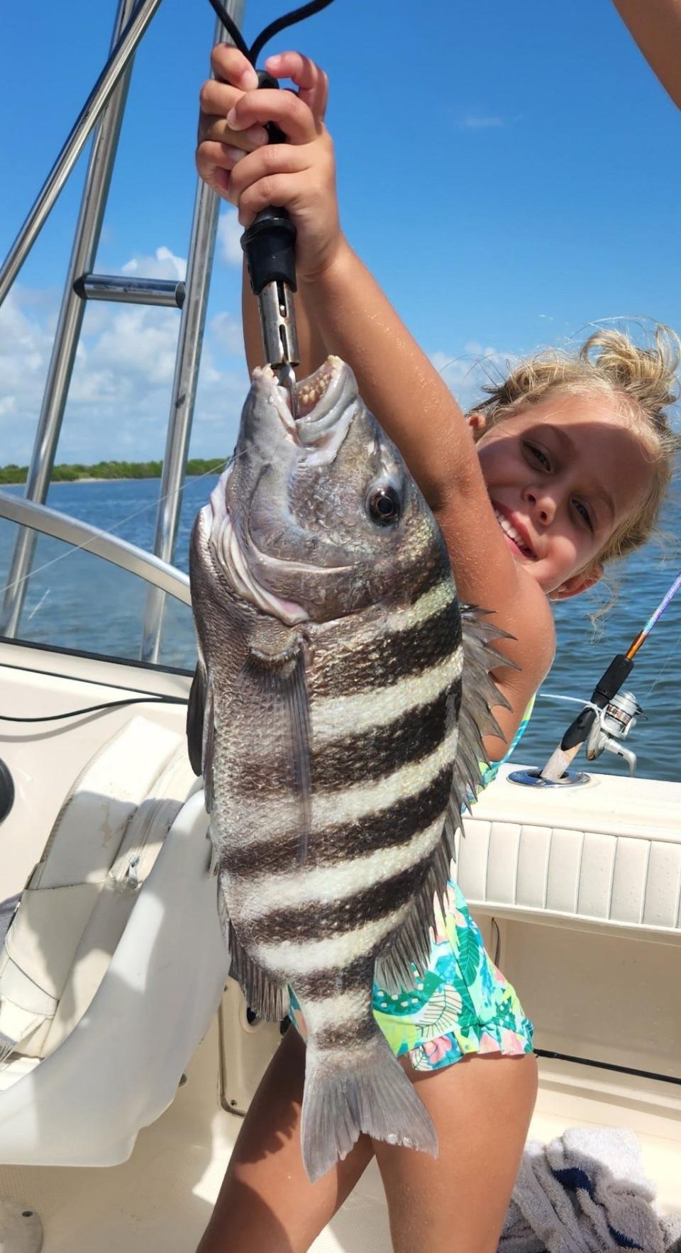 Maylee Butler, 8 years old, gives it all she's got to hold up this chunky sheepshead caught in the intracoastal.