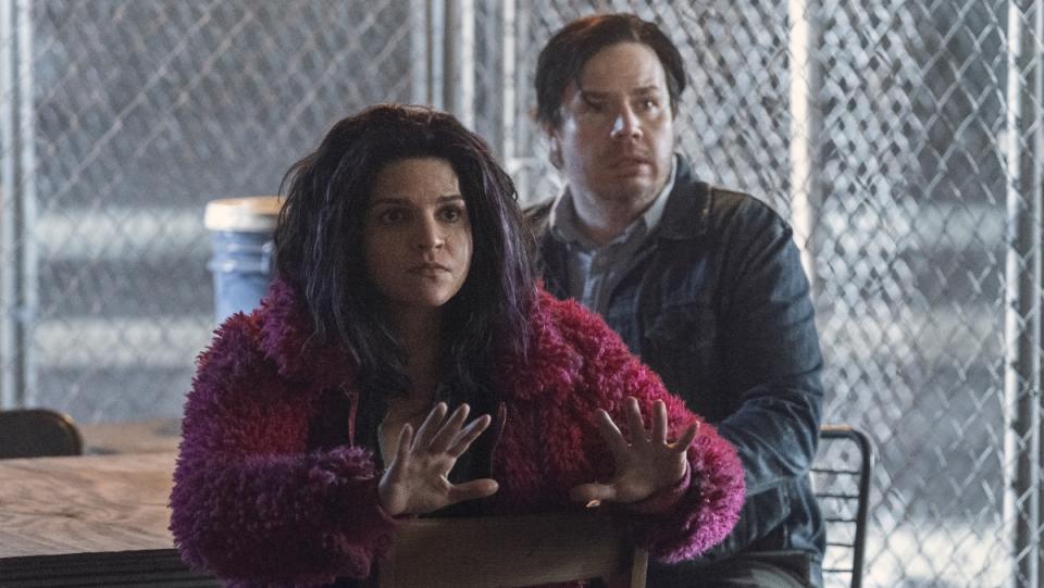 A Latina woman wearing a fur pink coat and a white man sit at a table