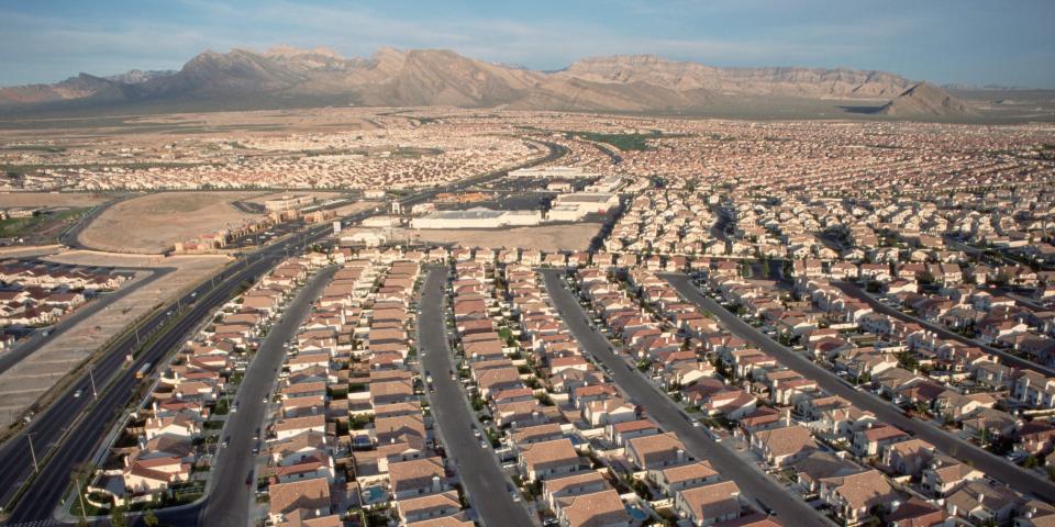 Rows of identical homes with uniform driveways and streets stretch towards the desert